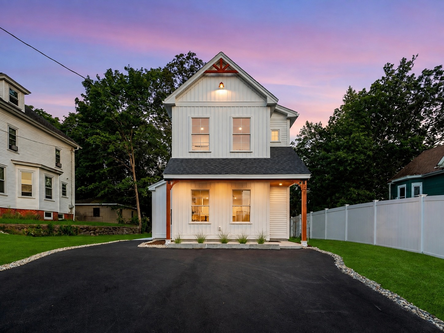 Completed farmhouse-style home at dusk with pink sunset sky