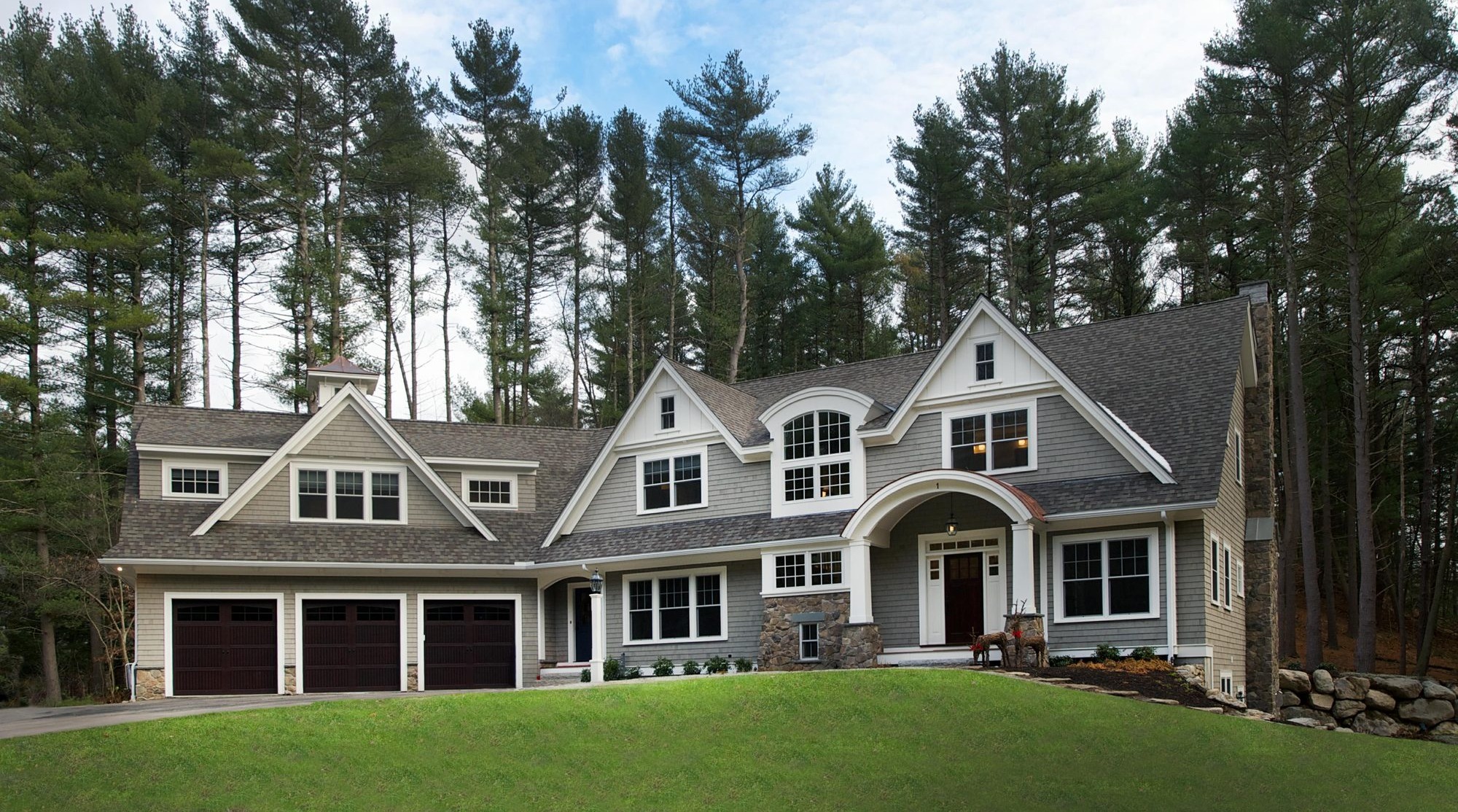 Large custom shingle-style home with three-car garage, cropped to the tree line